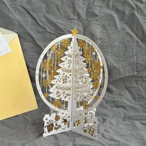 Close-up of 3D Christmas pop-up card featuring a white tree with gold snowflakes and envelope