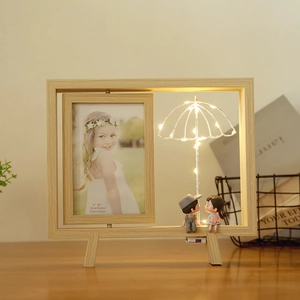 Détail d'un cadre photo rotatif en bois avec lampe LED parapluie et figurines de couple