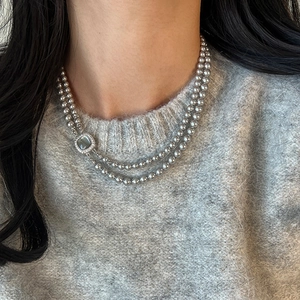 Close-up of double-layer grey pearl necklace with a vintage zircon square clasp on a sweater