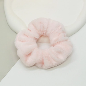 Gros plan d'un chouchou en peluche rose doux sur un plateau décoratif blanc