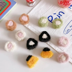 Close-up of colorful plush hair clips in various shapes including circles and triangles