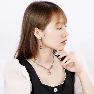 Elegant silver heart pendant necklace and matching drop earrings set worn by model