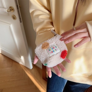 Mini plush cream cosmetic bag with colorful polka dots held in hand for size context