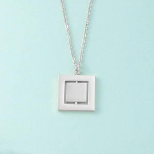 Detailed view of silver rotating double geometric square pendant on a metal chain