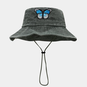 Détail de la broderie papillon bleu sur le chapeau de soleil en denim gris délavé