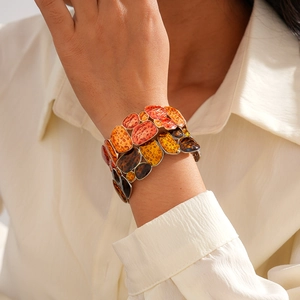 Detail of ethnic geometric enamel stretch bracelet on wrist with autumn knit sleeve