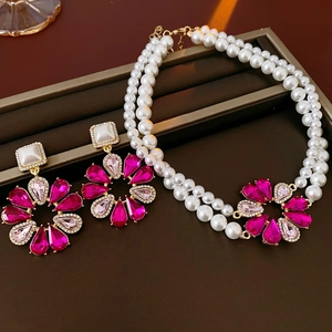 Vista dettagliata del set di gioielli con fiori di gemme rosa e eleganti perle bianche