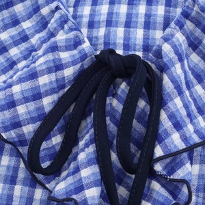 Detailansicht von blau-weiß kariertem Stoff mit einer dunkelblauen Baumwollschleife