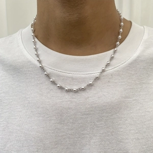 Close-up of retro hip-hop necklace with silver chain and white faux pearls on a male model