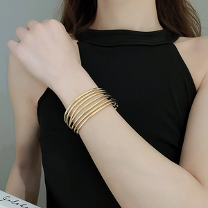 Close-up of stacked gold bangles with polished and engraved textures on a model wrist