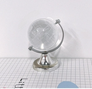 Macro detail of a crystal globe desk ornament with silver metal stand and grid background