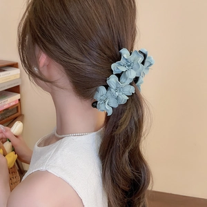 Gros plan sur une pince à cheveux fleurie bleu clair portée élégamment par un mannequin