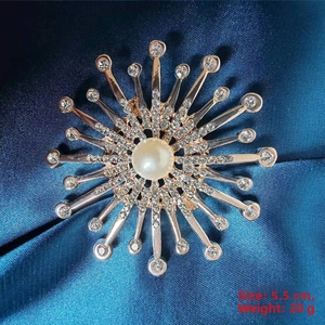 Detail view of 5.5cm rose gold sunburst brooch with pearl and crystals on blue silk