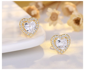 Macro shot of gold heart stud earrings featuring a central zircon surrounded by small stones