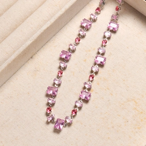 Close-up of pink and purple crystal gemstones on a silver chain necklace