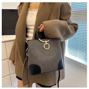 Detail of grey monogram bucket bag with gold ring handle and leather patchwork trim