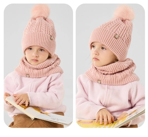 Close-up of pink knit winter hat with pom-pom and matching scarf for kids with soft texture