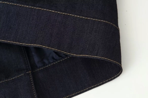 Gros plan des coutures orange contrastées sur un tissu denim bleu foncé