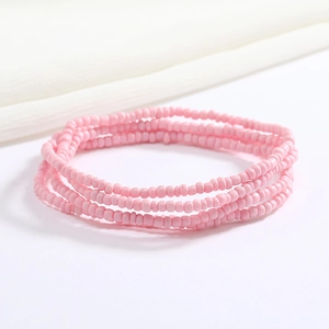 Close-up of pink handmade seed bead elastic body chain with matte finish on white linen