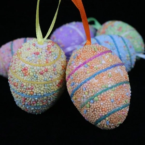 Macro shot of colorful foam Easter eggs with hanging ribbons against black background