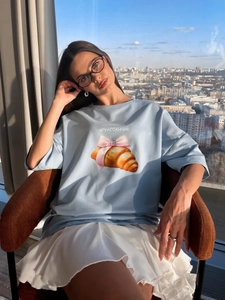 Oversize γαλάζιο βαμβακερό μπλουζάκι με σχέδιο κρουασάν και θέα στην πόλη στο φόντο