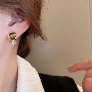 Close-up of vintage round tiger eye stud earring with a small crystal zircon accent