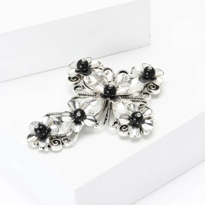 Vintage silver cross brooch with crystals and black beads on minimalist white display