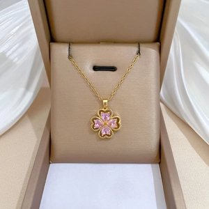 Elegant gold four-leaf clover necklace with pink heart gemstones in a jewelry gift box