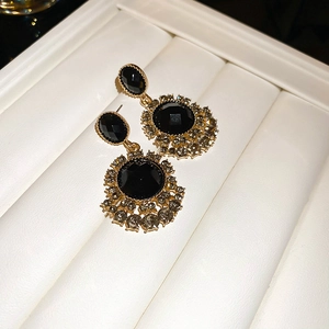 Macro shot of vintage black gemstone earrings with gold bead edges and crystal fringe