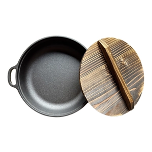 Pre-seasoned cast iron skillet with dual handles and carbonized wooden lid on white background