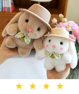 Close-up of fluffy white and brown plush rabbits wearing sun hats and floral bows