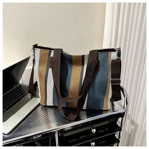 Close-up of a striped canvas tote bag with brown straps on a metal cart in a daily scene