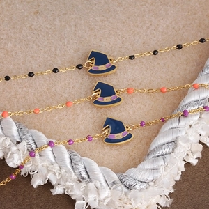 Detailed close-up of a blue witch hat enamel pendant on a golden beaded Halloween bracelet
