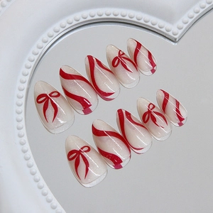 Faux ongles amande élégants avec base blanc nacré et motifs de nœuds ruban rouges