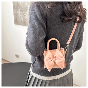 Rear view of a model wearing a pink crossbody bag with a large decorative bow detail