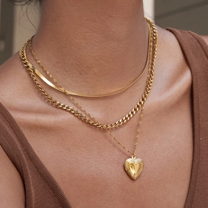 Detailed view of layered 18K gold stainless steel chains with carved heart locket pendant
