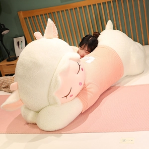 Large plush sheep toy wearing pink striped sweater in cozy bedroom setting close-up