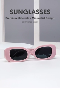 Pink rectangular sunglasses with thick vintage frames and dark lenses on display stand