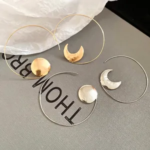 Asymmetric geometric hoop earrings with gold and silver crescent moon and disc charms