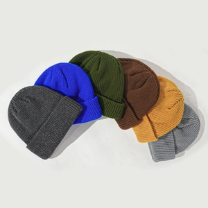 Row of colorful acrylic knit beanies in grey, blue, green, and yellow on white background