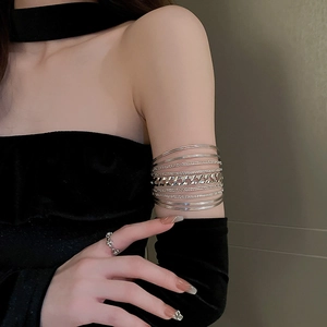 Detail of layered silver hollow geometric arm cuff worn on upper arm with stylish textures