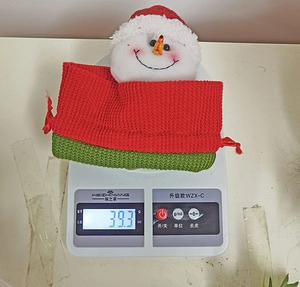 Detail view of a knitted Christmas drawstring gift bag with snowman head being weighed