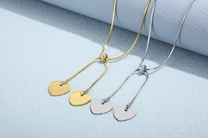Macro view of adjustable snake chain necklaces with polished heart pendants in gold and silver