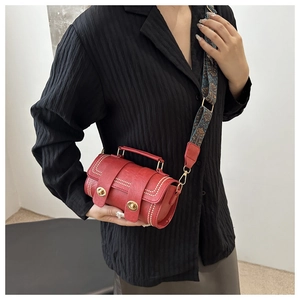 Red leather Boston bag with floral strap and rivet details shown on person