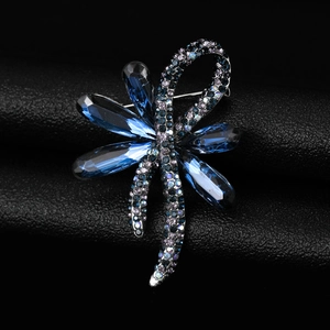 Macro detail of a crystal dragonfly brooch with blue teardrop stones and dark rhinestones