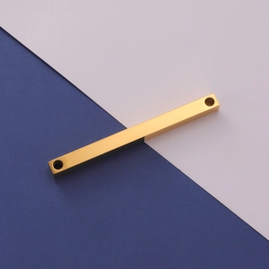 Macro detail of polished gold-finished rectangular stainless steel bar with dual-hole design