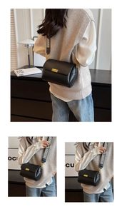 Détail du sac bandoulière en cuir noir avec boucle dorée et large sangle géométrique