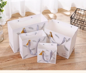 Macro view of white gift bags with silver feathers and gold star charms in four sizes
