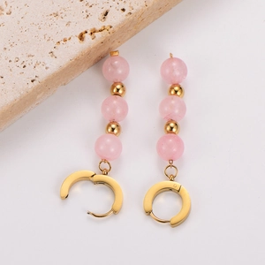 Detail of pink crystal beads and golden charms on stainless steel huggie earrings
