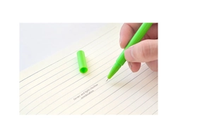 Close-up of bright green fine-point creative pen writing on lined paper with smooth ink